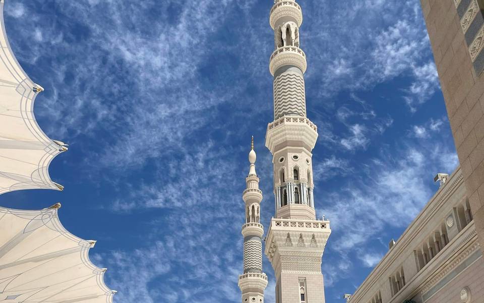 مآذن بيضاء ومظلات تحت سماء زرقاء في المدينة المنورة