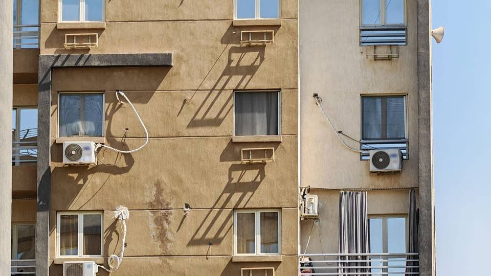واجهة عمارة سكنية تظهر عليها وحدات سبليت خارجية وحوامل لمكيفات الشباك