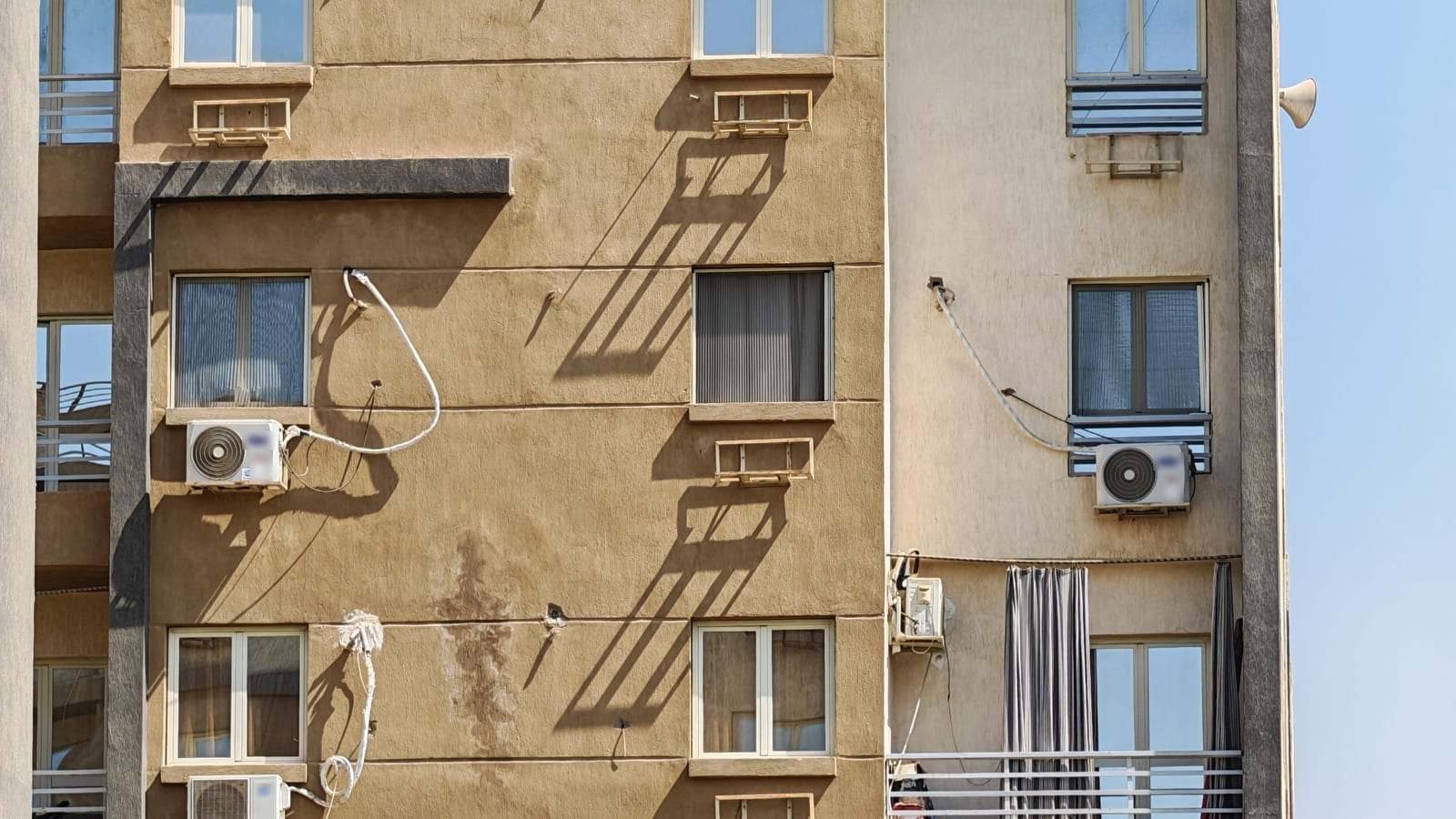 واجهة عمارة سكنية تظهر عليها وحدات سبليت خارجية وحوامل لمكيفات الشباك